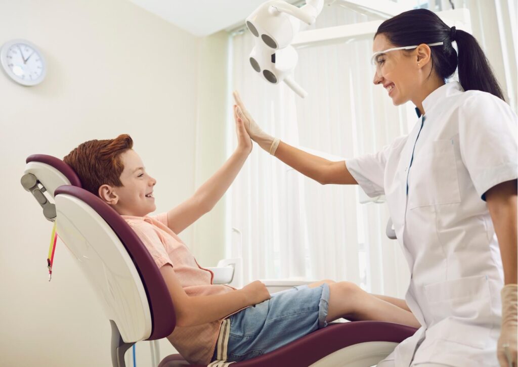 Young patient giving a high five to an orthodontist after a successful children's orthodontic checkup.