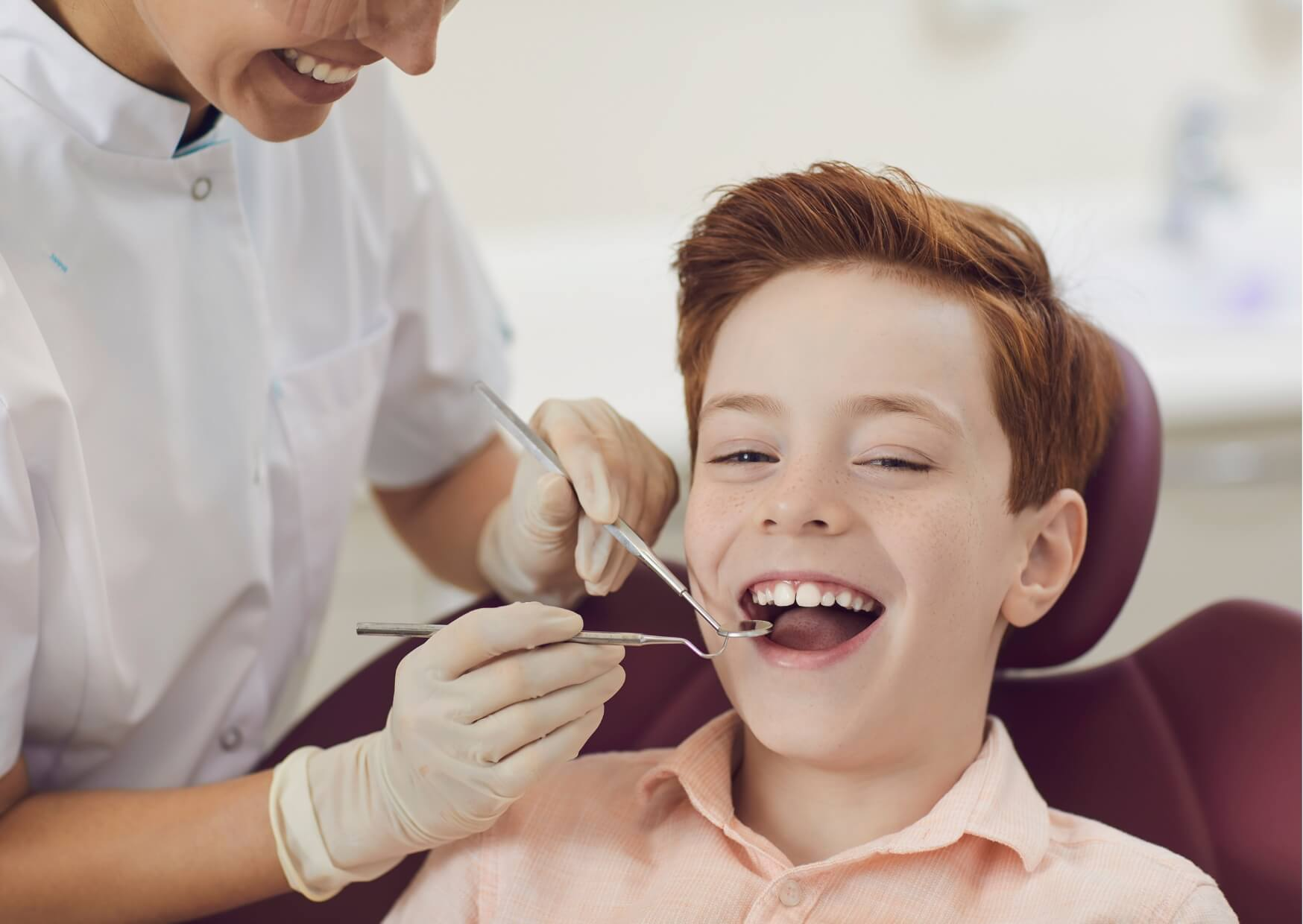 Child smiling during an orthodontic checkup as the orthodontist examines developing teeth and bite alignment.